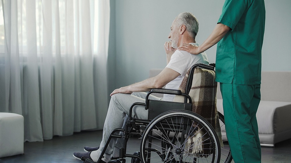 Concerned adult child speaking with an elderly parent in a nursing home, highlighting the importance of recognizing signs of elder abuse and neglect.