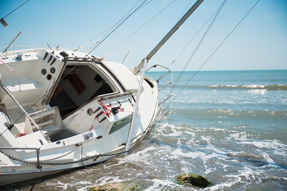 Photo of a damaged boat after a boating accident on the water, with debris visible, showcasing the aftermath of a personal injury incident.