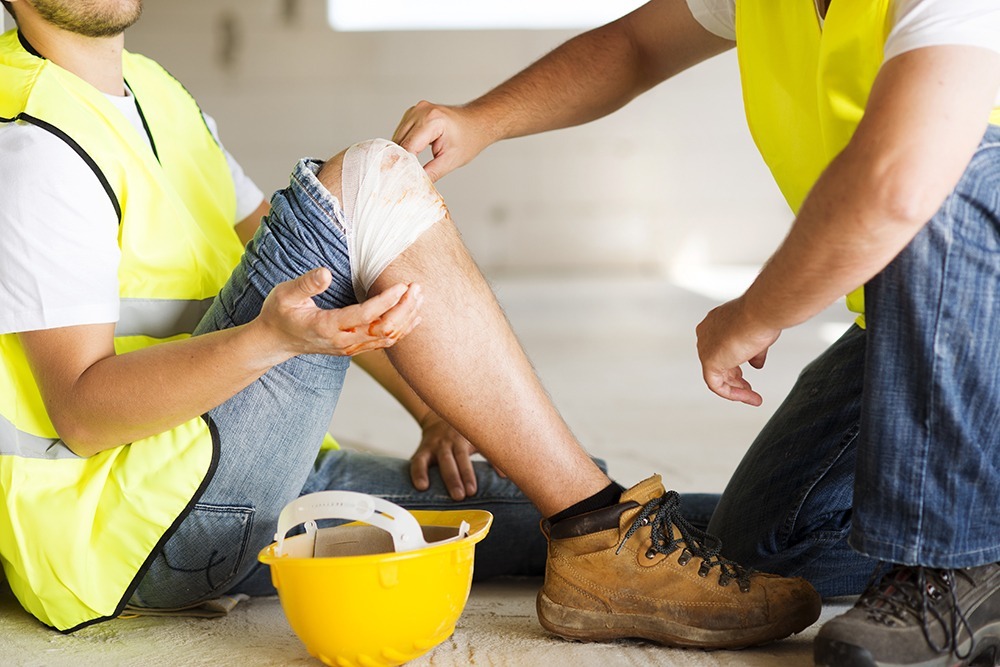 Workplace injury in Florida: injured worker with medical attention at the scene of an accident in a construction site.